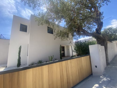 Villa blanche contemporaine avec clôture en bois à Casa di Sadrea, Lecci, entourée d'aménagement méditerranéen et d'arbres matures