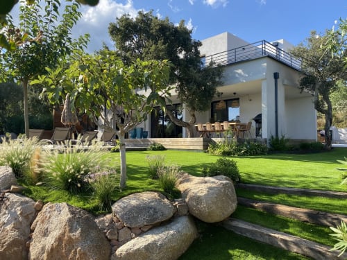 Villa blanche moderne à Casa di Sadrea à Lecci avec pelouse impeccable, arbres matures et éléments en pierre dans le jardin