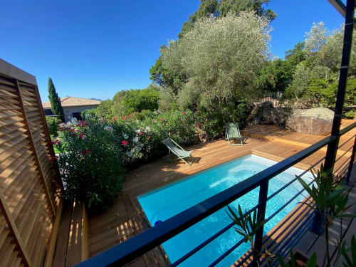 Vue lumineuse de la piscine de la villa Casa di Sadrea à Lecci avec piscine turquoise, terrasse en bois et jardins méditerranéens