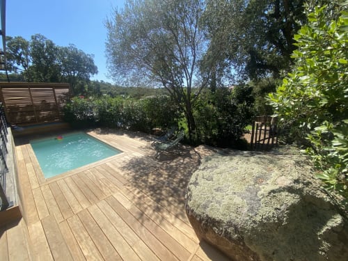 Piscine turquoise avec terrasse en bois entourée de végétation luxuriante à la villa Casa di Sadrea à Lecci, Corse