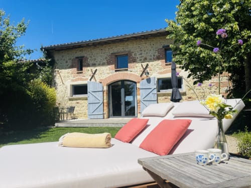Maison Monsieur Léger, gîte de vacances à Montaut avec façade en pierre, transats et fleurs violettes