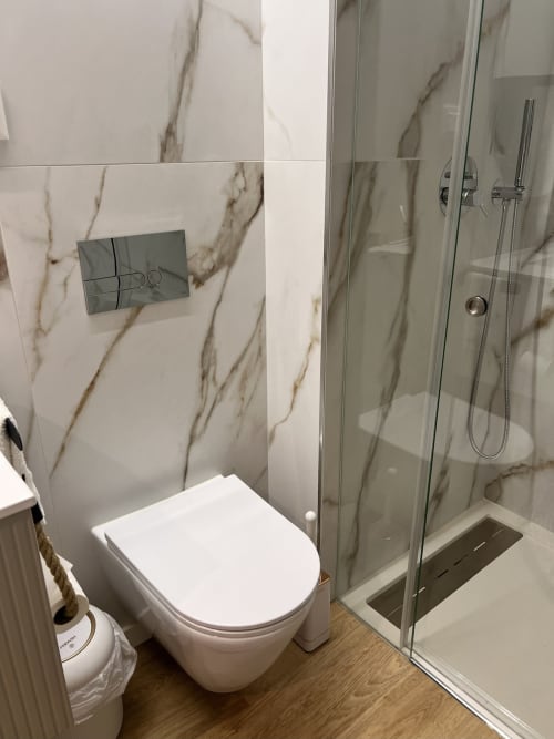 Casa de banho moderna com azulejos efeito mármore, sanita branca e cabine de duche em vidro em Timeless Vacations Arcozelo