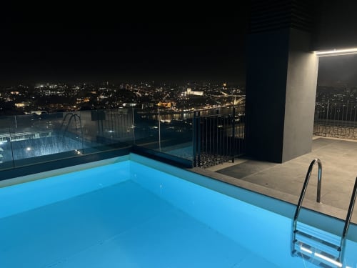 Piscina iluminada na cobertura da Torre do Douro com vista para a paisagem noturna e rio de Arcozelo