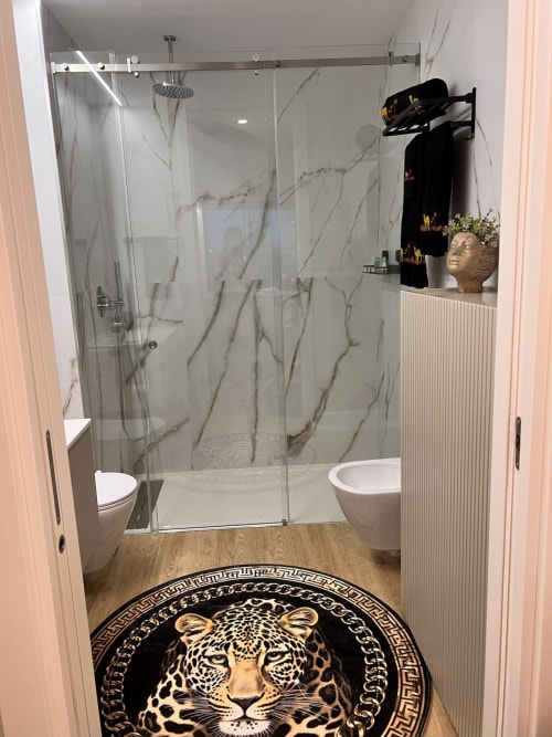 Banheiro moderno na Timeless Vacations Arcozelo com chuveiro de mármore, tapete estampado de leopardo e vista para o rio.