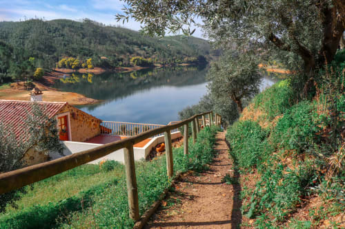 Vista do rio da Quinta da Mata de Baixo com oliveira, cerca de madeira e encosta florestada em Cagida, Portugal
