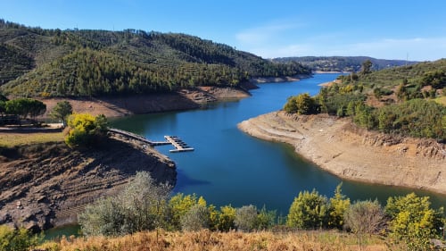 Lago de reservatório azul cênico com colinas florestais e pequeno cais na Quinta da Mata de Baixo em Cagida, Portugal