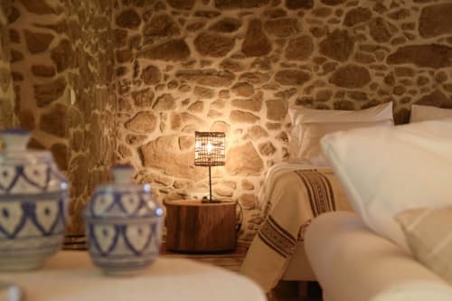 Quarto aconchegante em pedra na Quinta da Mata de Baixo com roupa de cama branca, criado de madeira e iluminação quente