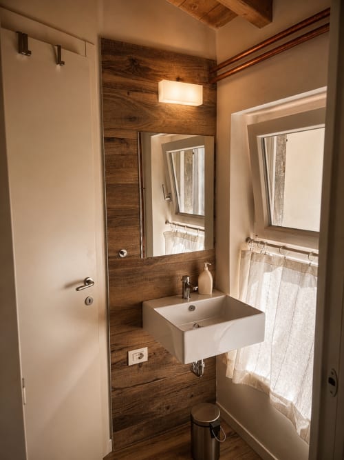 Modernes Badezimmer im B Loft Apartment im Bergamo City Center mit Holzakzentwand, Waschbecken, Spiegel und Fenster