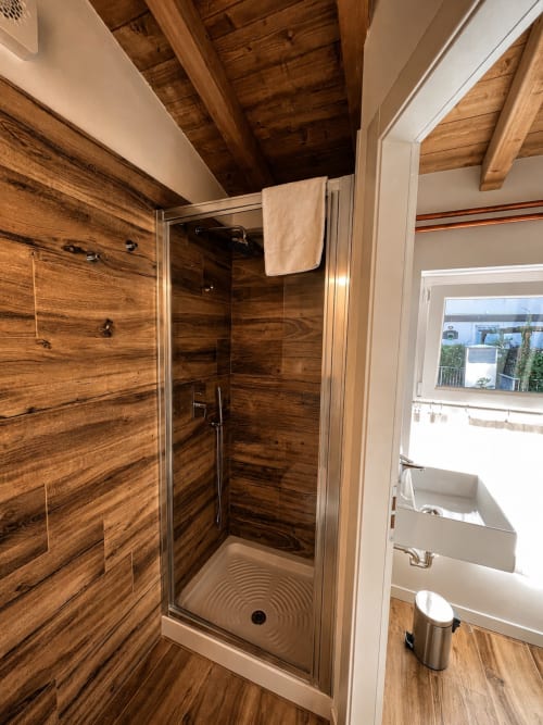 Modernes Duschbad mit Holzoptik-Fliesen und Glasabtrennung in Bergamo-Apartment