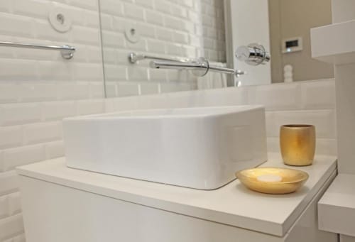 Banheiro moderno em apartamento do Porto com cuba branca, azulejos metrô, metais cromados e detalhes dourados na bancada
