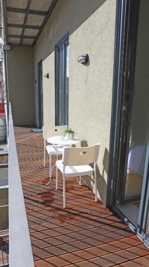 Varanda de apartamento no Porto com conjunto de jantar branco, piso em terracota e paredes creme com moldura metálica