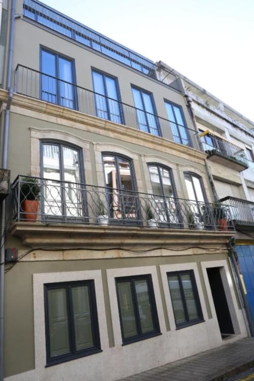 Edifício de apartamentos Timeless Vacations no Porto com varandas, janelas amplas e vista para jardim em fachada histórica restaurada