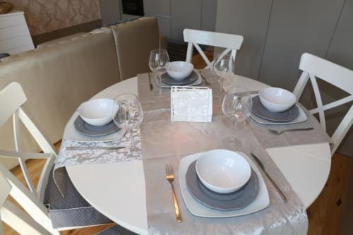 Mesa de jantar redonda elegante para quatro na apartamento Timeless Vacations Porto, com cadeiras brancas e mesa posta formalmente