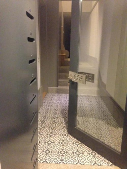 Corredor estreito em apartamento no Porto com piso de azulejos decorativos e paredes brancas que levam aos quartos