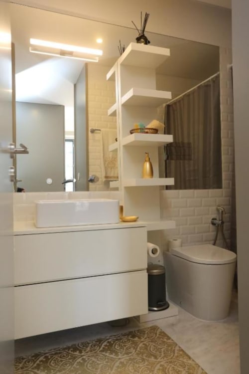 Banheiro moderno no apartamento Timeless Vacations Porto com penteadeira branca, prateleiras flutuantes, espelho grande e sanitário.
