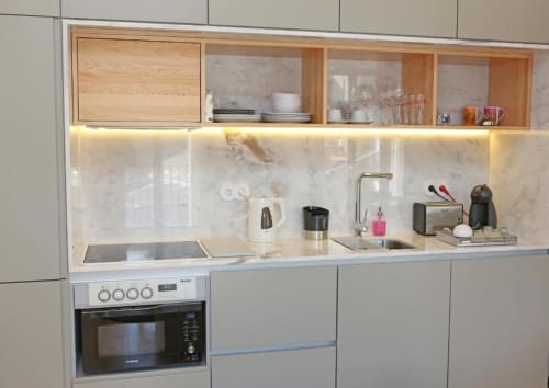 Cozinha moderna em apartamento no Porto com armários brancos, bancada em mármore, forno embutido e unidades de armazenamento em madeira quente.