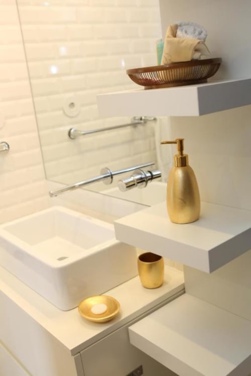 Banheiro moderno do apartamento Timeless Vacations Porto com pia branca, acessórios dourados e espelho suspenso