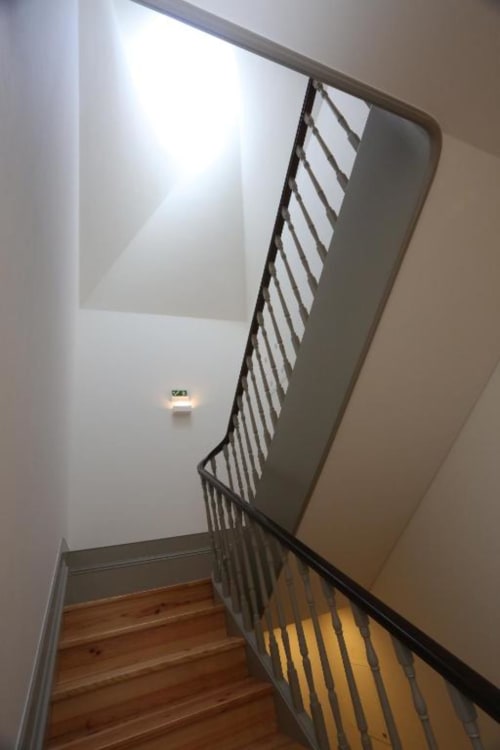 Escada com corrimão metálico em apartamento no Porto, degraus de madeira com luz natural