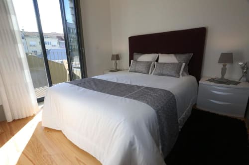 Quarto moderno em apartamento no Porto com camas de casal, cabeceira escura, assoalho em madeira, varanda e vista da cidade na Timeless
