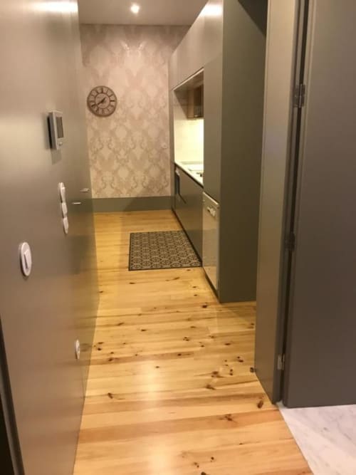 Corredor moderno com piso de madeira, paredes verde-pálido e relógio decorativo no apartamento Timeless Vacations Porto