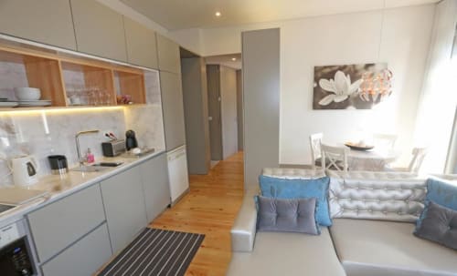 Moderno apartamento no Porto com cozinha integrada, sala de jantar, piso em madeira e sofá confortável com detalhes azuis
