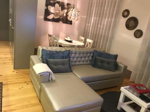 Sala de estar moderna com sofá em L bege, almofadas azuis, piso de madeira, zona de refeições e arte mural decorativa no Porto