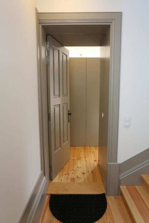 Entrada moderna de apartamento no Porto com piso em madeira, paredes brancas e guarda-roupa embutido na Timeless Vacations