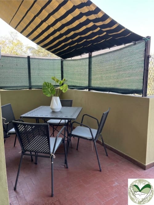 Terrazza ombreggiata presso I Dolci Appartamenti Ascani Roma con tavolo da pranzo, sedie e schermi verdi per la privacy