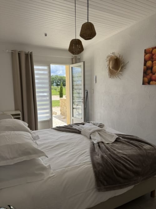 Lichte slaapkamer in L'arbre Qui Chante B&B met tweepersoonsbed, hangende verlichting en uitzicht op de tuin in Saint Sauveur de Cruzières