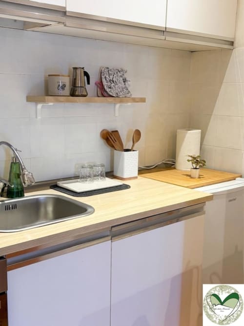 Banco cucina moderno con top in legno, armadi bianchi, lavello, portautensili in legno e mensola sospesa a I Dolci