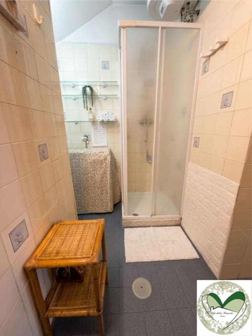 Bagno moderno presso I Dolci Appartamenti Ascani Roma con cabina doccia, piastrelle beige e arredamento in legno
