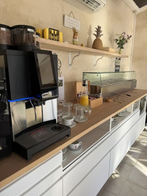 Bar à café moderne à L'arbre Qui Chante B&B avec machine à espresso, comptoir bois et décoration d'ananas en pot à Saint