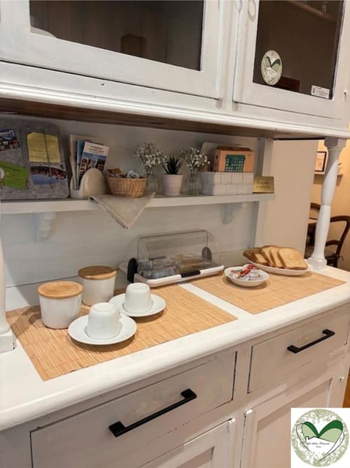 Moderna cucina dell'hotel I Dolci Appartamenti Ascani a Roma con mobili bianchi, piano in legno, tazze bianche e