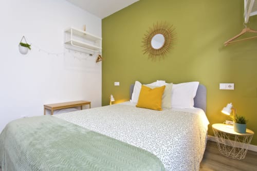 Chambre lumineuse au 100 Contos Porto avec mur jaune, lit queen, miroir doré, étagères blanches, style moderne