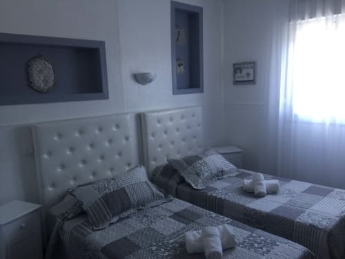Chambre twin de Luberon L'Hôtel à Apt avec têtes de lit capitonnées blanches, literie grise et décor moderne