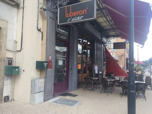 Devanture de l'hôtel Luberon à Apt, France avec terrasse extérieure et auvent bordeaux