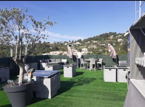 Terrasse sur le toit du Luberon L'Hôtel à Apt avec transats, parasols roses et vue sur les collines