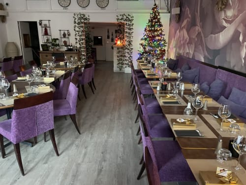 Salle à manger élégante de Luberon L'Hôtel à Apt avec chaises violettes, sapin de Noël décoré et guirlande festive