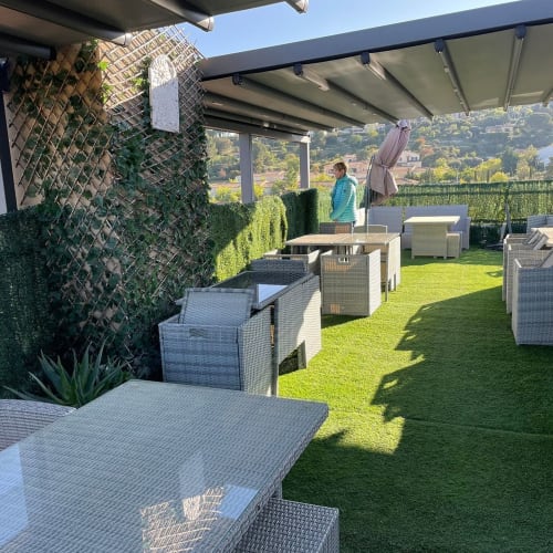 Terrasse panoramique du Luberon L'Hôtel à Apt avec mobilier en osier, pelouse verdoyante et vue sur la vallée
