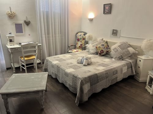 Chambre Luberon L'Hôtel à Apt avec lit queen-size, literie grise, bureau, mobilier blanc et coussins de décoration