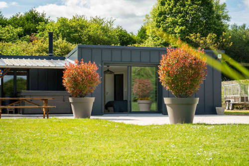 Chalet moderne aux tons sombres avec jardinières rouges automnales au gîte Étang du Rameau d'Accolade à Châteaudun