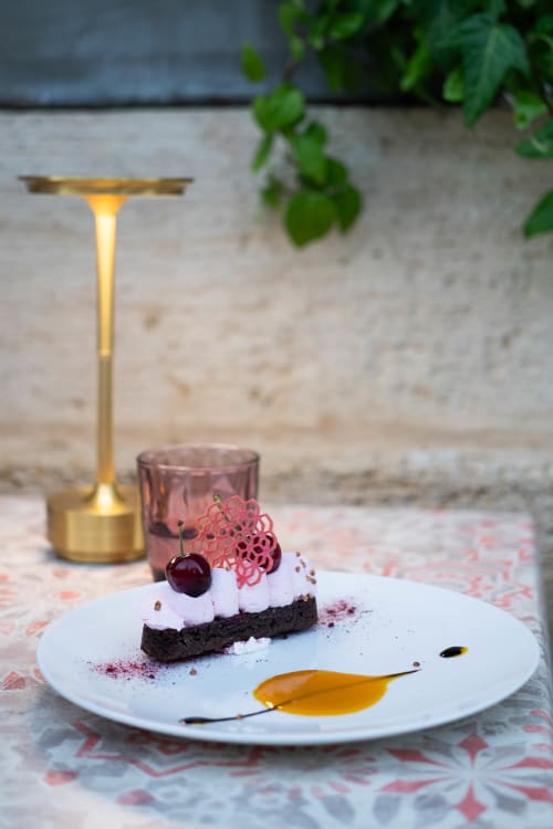 Elegant plated dessert with chocolate cake, white cream, cherry and pink decoration at Pavillon Des Millesimes, Lussac