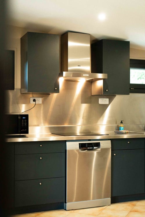 Cuisine moderne du gîte Accolade avec électroménagers en acier inoxydable, armoires sombres et hotte éclairée