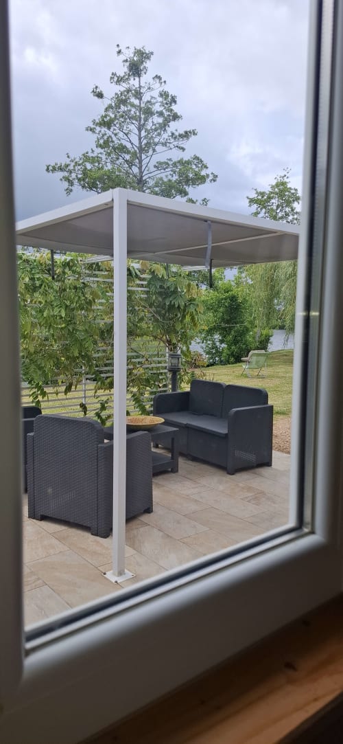 Pergola blanche moderne avec salon en rotin noir vue sur lac au Châteaudun