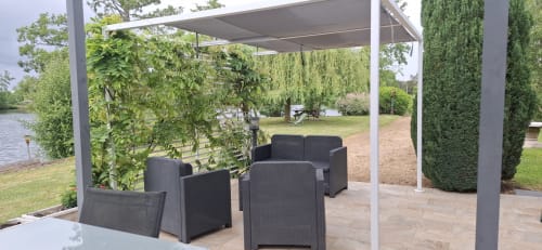Pergola contemporaine avec salon en rotin noir dominant le lac au gîte Accolade, Châteaudun