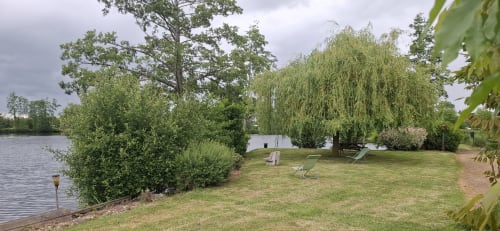 Vue privée du lac du gîte L'étang de la Chartière à Châteaudun, France avec pelouse verdoyante et saules pleureurs