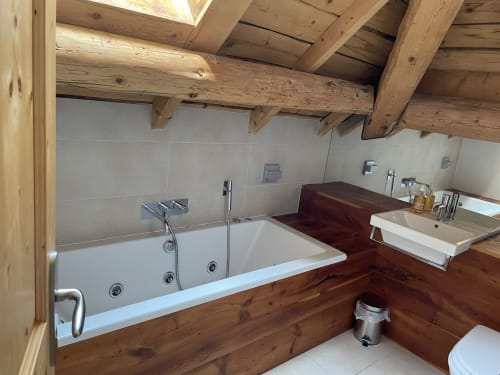 Salle de bain luxueuse avec baignoire îlot, double vasque et poutres en bois au Chalet Savoyard à La Plagne