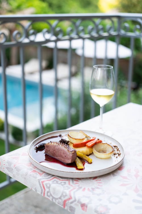 Elegant plated duck dish with vegetables and white wine by pool at Pavillon Des Millésimes, Lussac