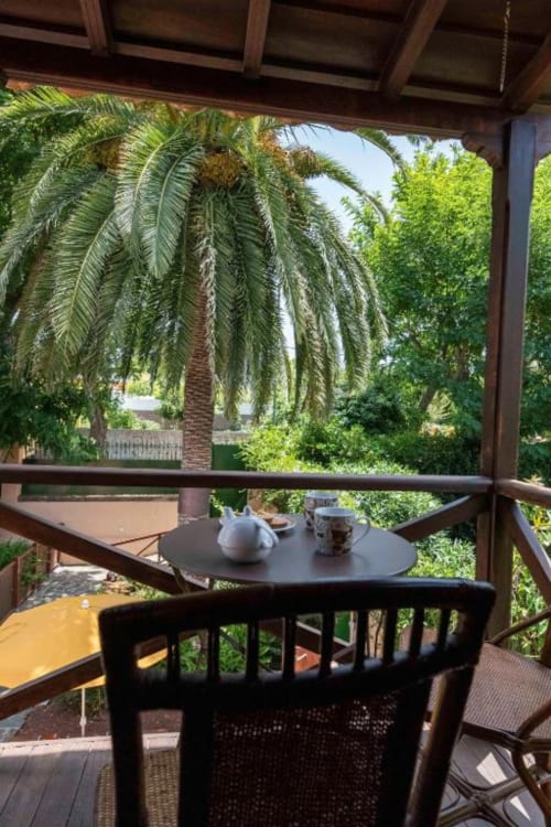 Patio sombreado en Haller Homes en Canarias con palmeras, mobiliario de exterior y piso de terracota