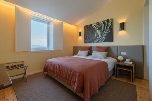 Quarto duplo moderno do hotel Douro Land em Peso da Régua com vista de montanha, cabeceira cinza, roupa de cama terracota e ambiente acolhedor